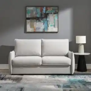 Jinn Modern Sleeper Sofa in Beige Chenille, styled as a couch in a contemporary living room with art and a table lamp.