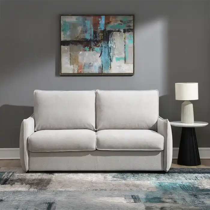 Jinn Modern Sleeper Sofa in Beige Chenille, styled as a couch in a contemporary living room with art and a table lamp.
