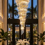 Large gold crystal chandelier in a two-story Tampa, FL foyer with palm tree views
