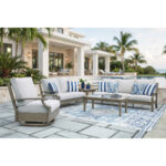 Complete Milas beige outdoor furniture collection arranged on luxury poolside patio with sofa, loveseat, swivel chair, tables and blue patterned rug