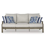 Front view of Milas beige aluminum outdoor sofa with wood-look frame, beige Nuvella+ cushions, and blue floral throw pillows on white background