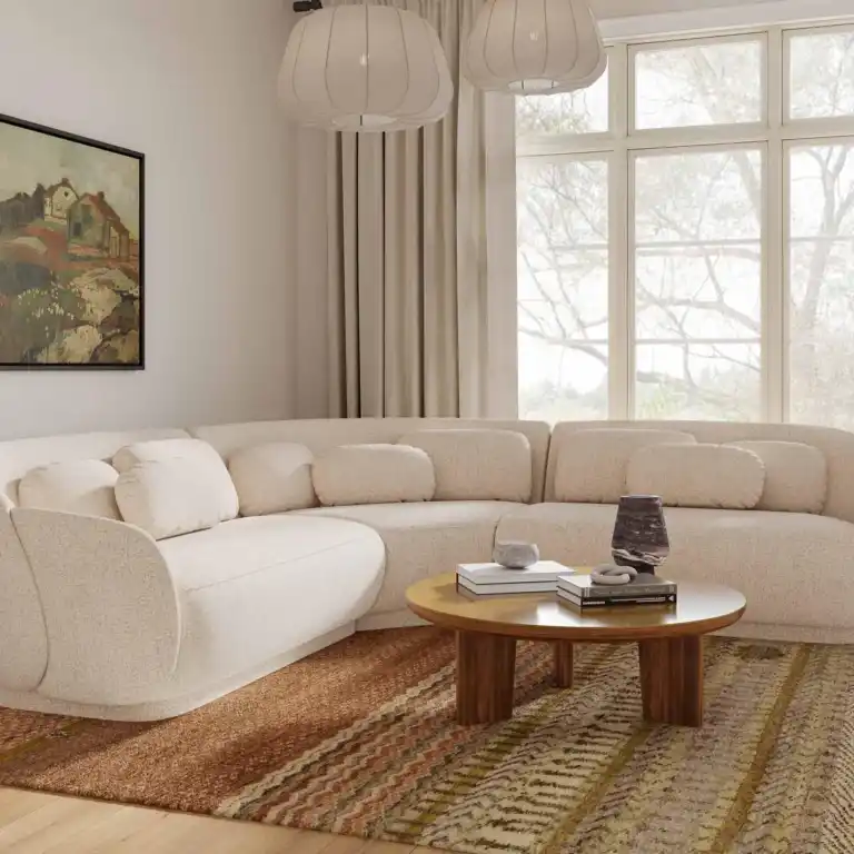 Large modern sectional sofa in off-white bouclé fabric, L-shape configuration, paired with a round wood coffee table and contemporary lighting. Displayed as modern living room furniture at a trusted furniture store in Tampa, FL.