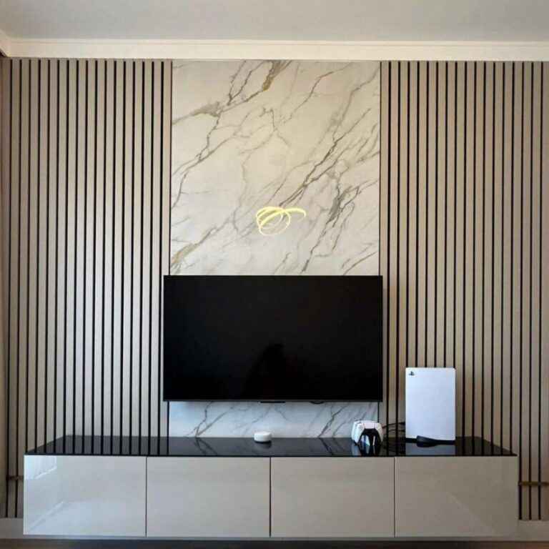 Marble-patterned PVC wall panels behind a modern TV unit with decorative wood paneling.