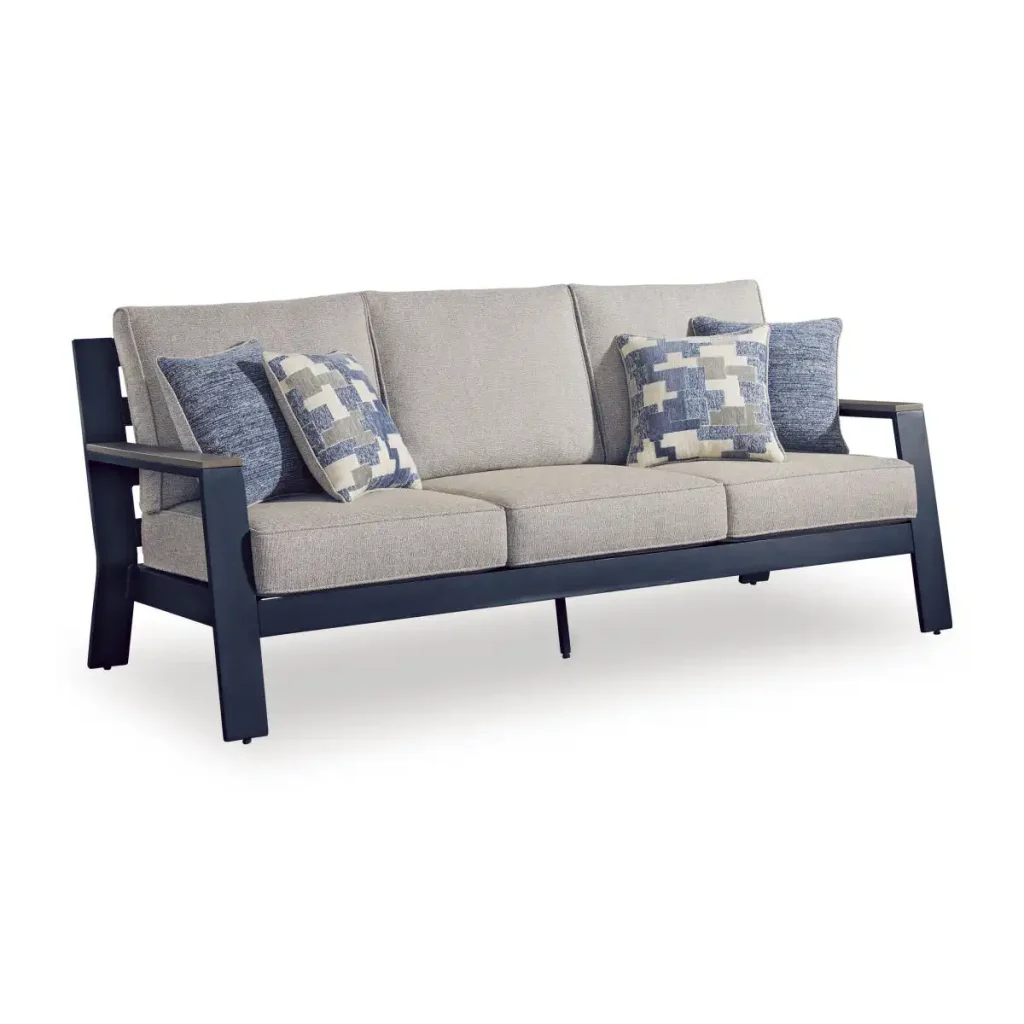 Three-quarter front view of Sile navy blue outdoor sofa with driftwood-look arms, light gray cushions, and blue geometric throw pillows on white background