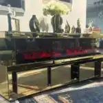 A close-up of the electric fireplace within a gold mirrored TV stand, showing the realistic red and orange flames.