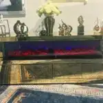 A side view of a gold mirrored fireplace TV stand with its drawers slightly ajar, revealing storage space.