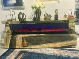 A side view of a gold mirrored fireplace TV stand with its drawers slightly ajar, revealing storage space.