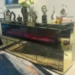 A gold mirrored TV stand with a striking red and purple electric fireplace and stylish home decor accents.