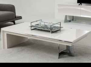 White rectangular modern coffee table with silver metal accents in a contemporary living room setting.